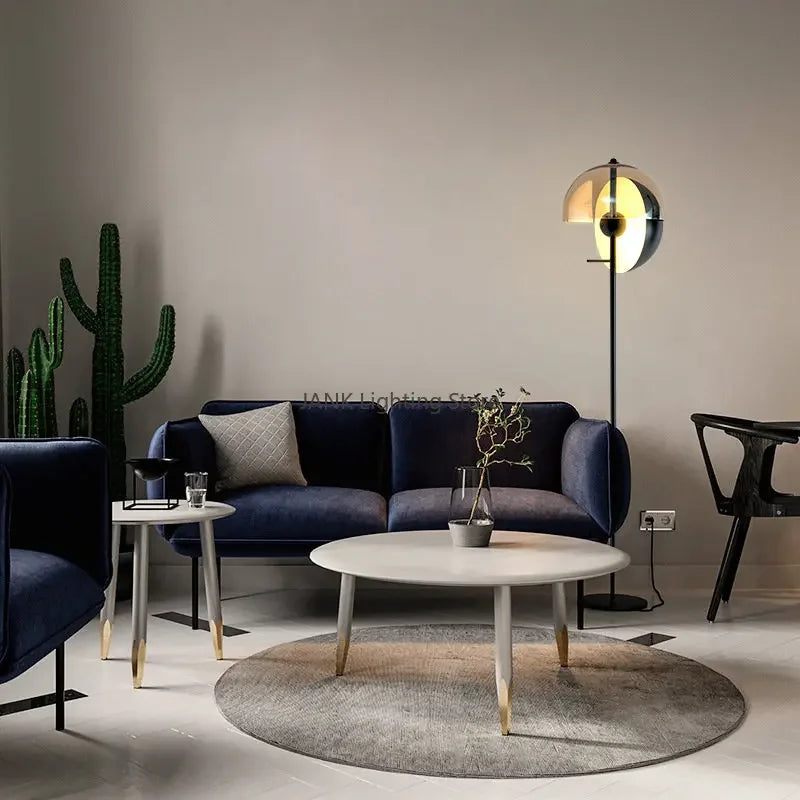Lunar Visor Floor Lamp anchoring a contemporary living room with navy velvet seating and warm neutral tones, sophisticated ambient lighting by Domus Collective.