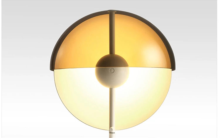 Front view of the Lunar Visor lamp head showing its symmetrical split-sphere design with warm amber upper dome and cream lower diffuser on white stem, elegant simplicity by Domus Collective.