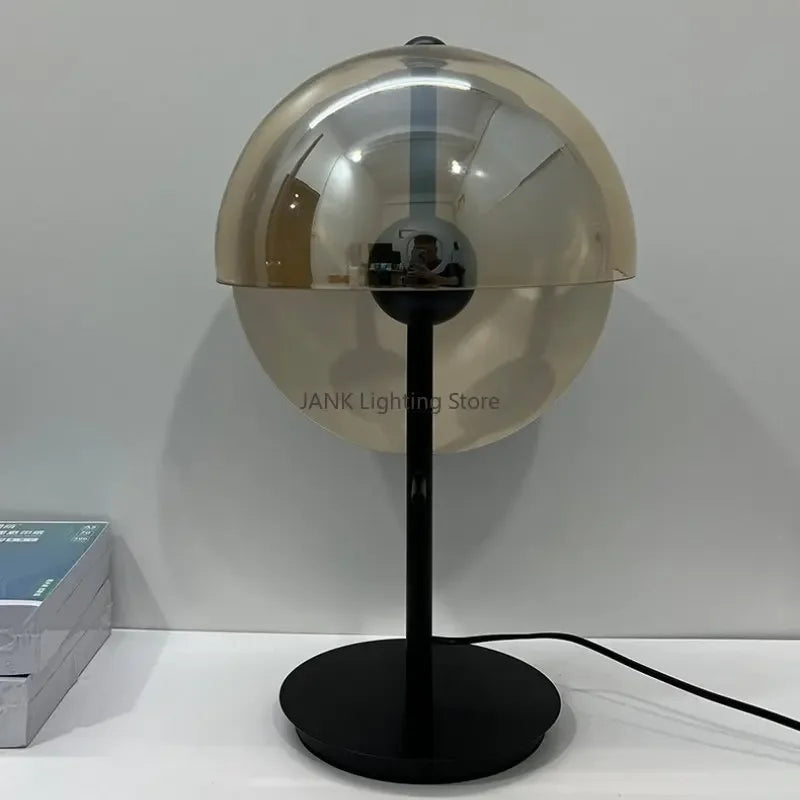 Lunar Visor Table Lamp in cognac-tinted glass with reflective spherical shade on slim black pedestal base, futuristic sculptural design by Domus Collective.