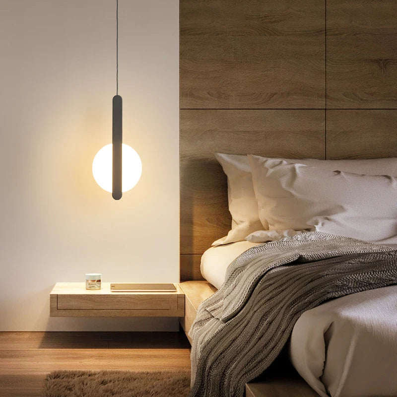 Matchstick Slice Pendant Light with frosted glass globe and matte black metal bar, a minimalist bedside fixture casting warm ambient light for restful evenings, by Domus Collective.