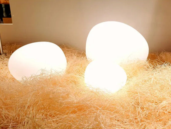 Moonstone Glow Table Lamps displayed on natural straw bedding, organic gemstone-inspired frosted glass forms with warm diffused lighting creating cosy atmosphere, by Domus Collective.