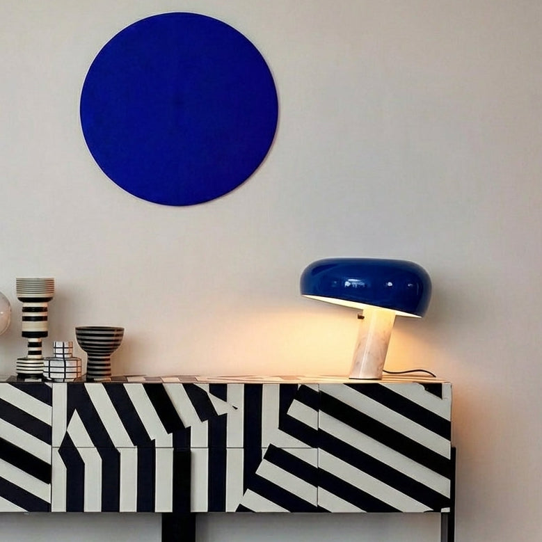 Cobalt blue Mushroom Beam Table Lamp with distinctive domed shade on angled marble base displayed on a graphic striped sideboard, bold modern statement lighting by Domus Collective.