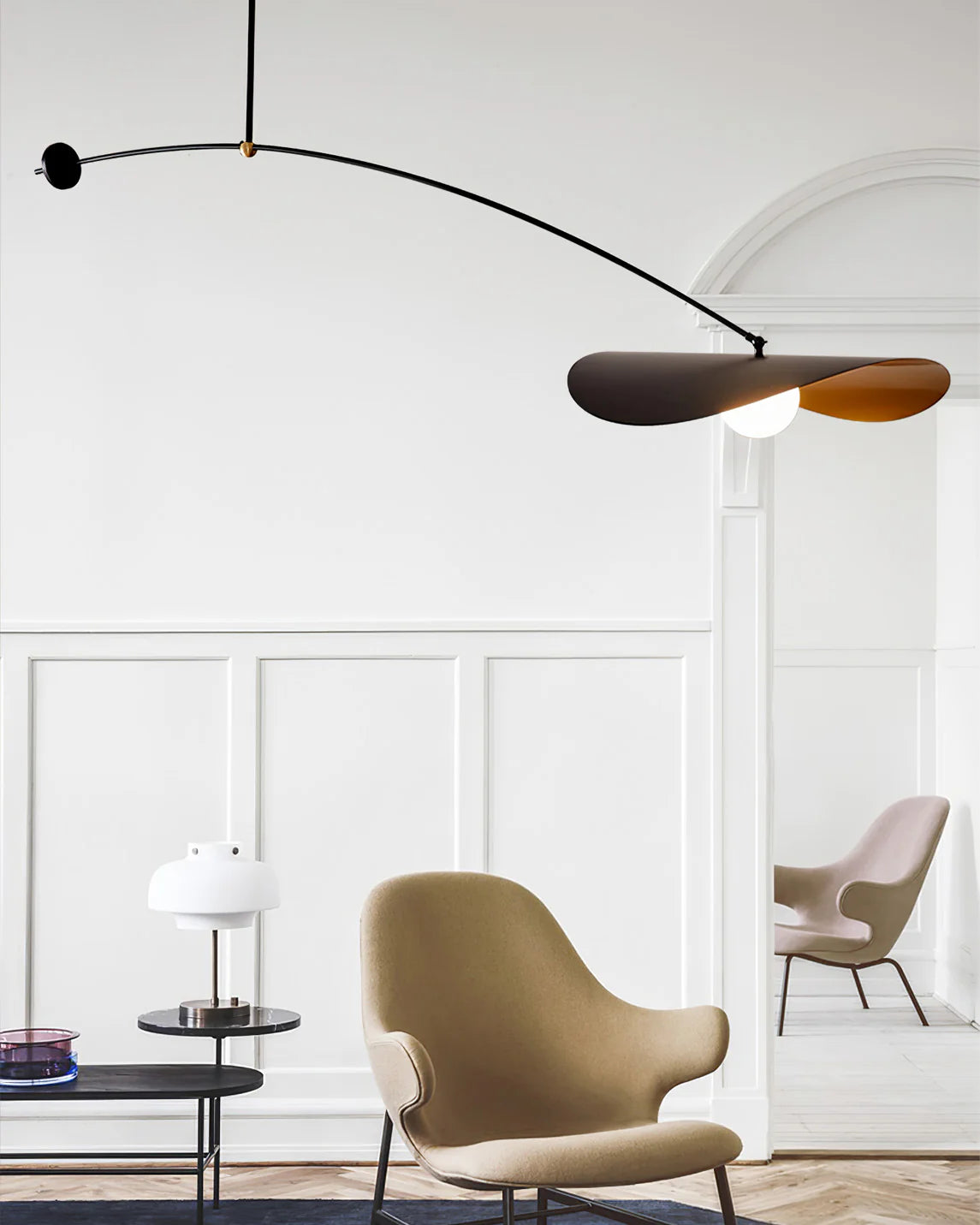 Papilla Pendant Light suspended in a classic Parisian interior with white wainscoting, its black and gold butterfly shade design creating a striking contrast with traditional architecture by Domus Collective.