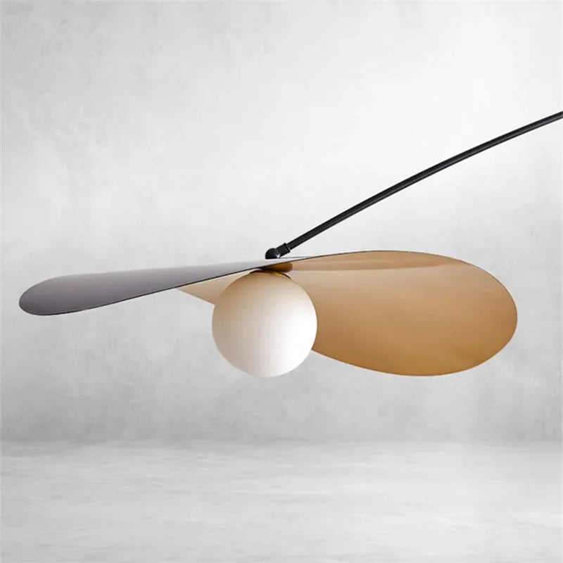 Detail of the Papilla Pendant Light shade assembly showing overlapping black and gold metal petals cradling a frosted glass globe, highlighting the nature-inspired craftsmanship and soft light diffusion.