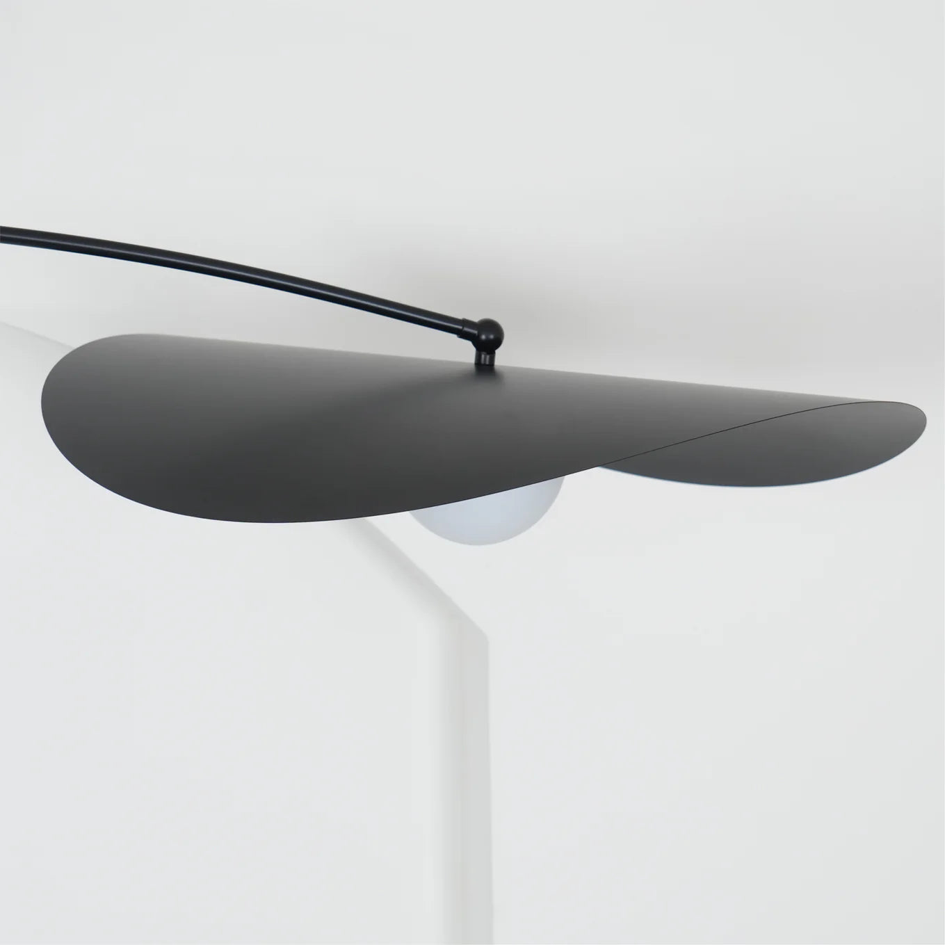Side profile of the Papilla Pendant Light's dual-petal shade in matte blackwith frosted globe bulb partially visible, showcasing the organic sculptural silhouette and refined metalwork by Domus Collective.