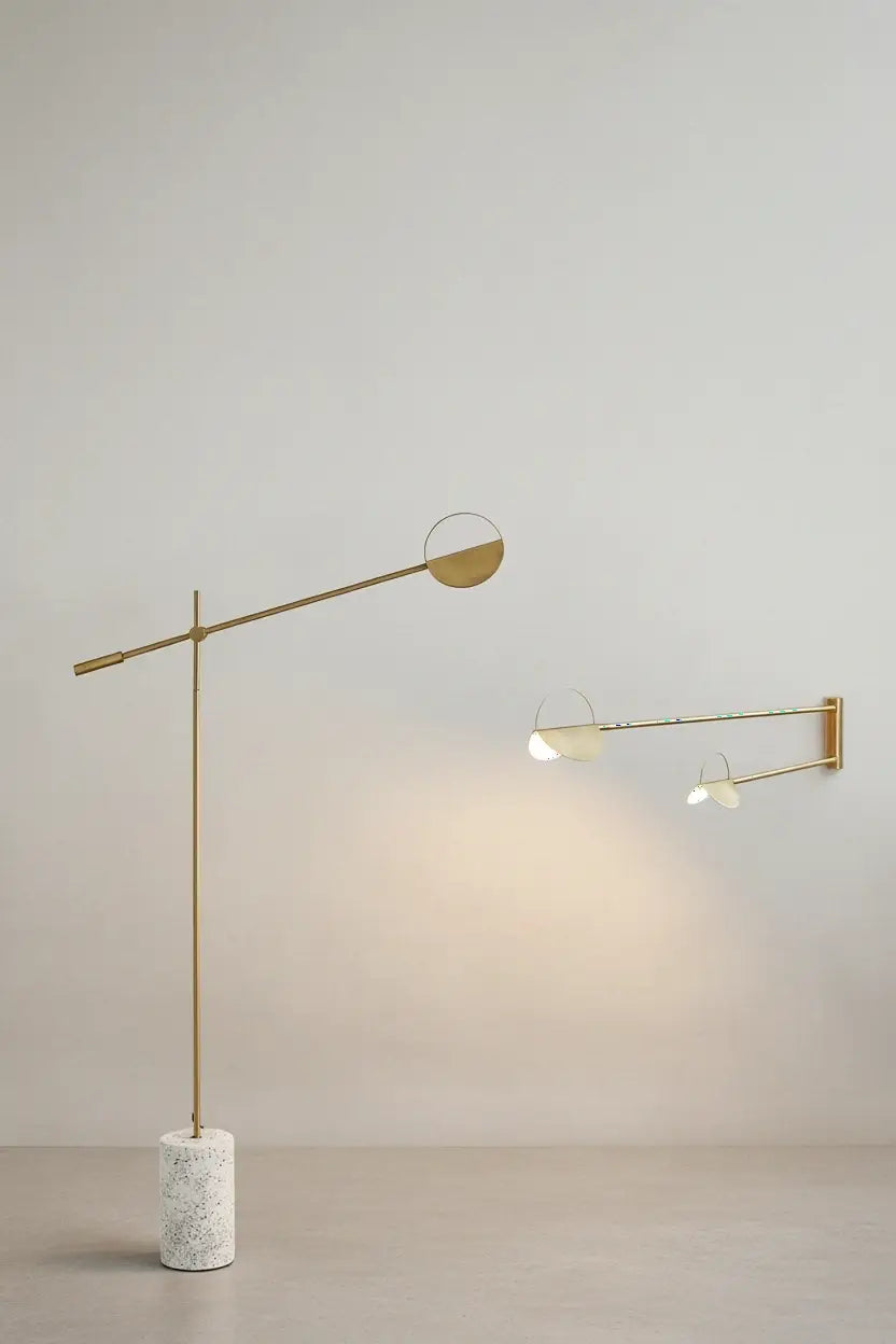 Gold Petal Poise Floor Lamp with white terrazzo base shown with double-arm wall light variant casting warm directional glow,a Domus Collective where natural materials meet refined metallic craftsmanship.