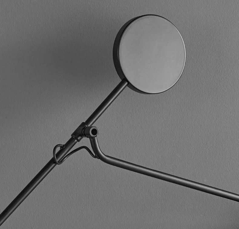 Close-up of the Refined Span Wall Light's articulating pivot mechanism and disc counterweight in matte black metal, highlighting the sculptural engineering that enables flexible positioning.