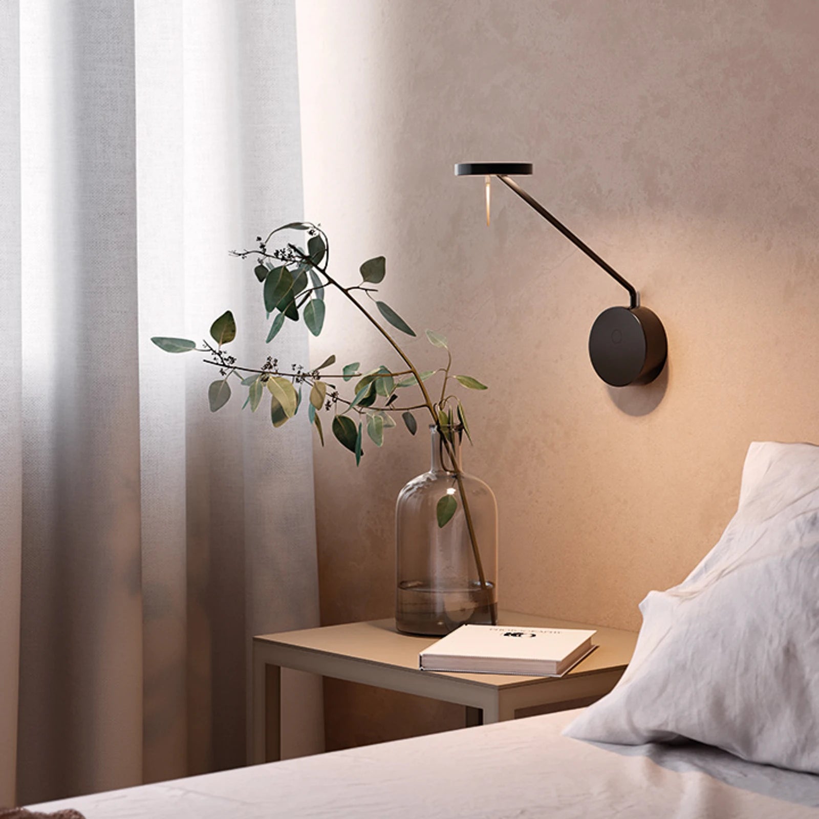 Compact Refined Span Wall Light with circular backplate and angled arm in dark bronze finish, offering focused bedside illumination with understated designer sophistication by Domus Collective.