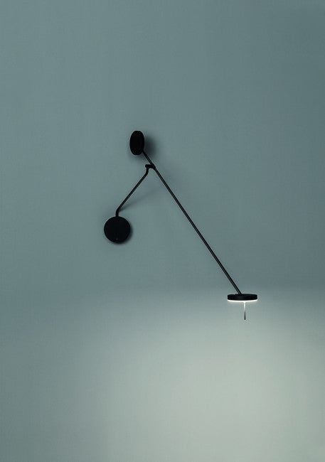 Refined Span Wall Light mounted on grey wall, showcasing the full articulating arm design with dual counterweight discs and illuminated circular head in matte black by Domus Collective.