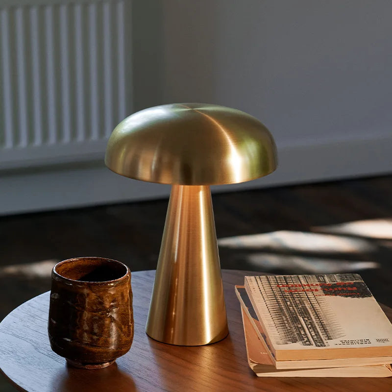 Shroom Aura Portable Lamp in warm brushed gold finish on wooden side table, bringing luxurious warmth and sculptural presence to sunlit living spaces by Domus Collective.