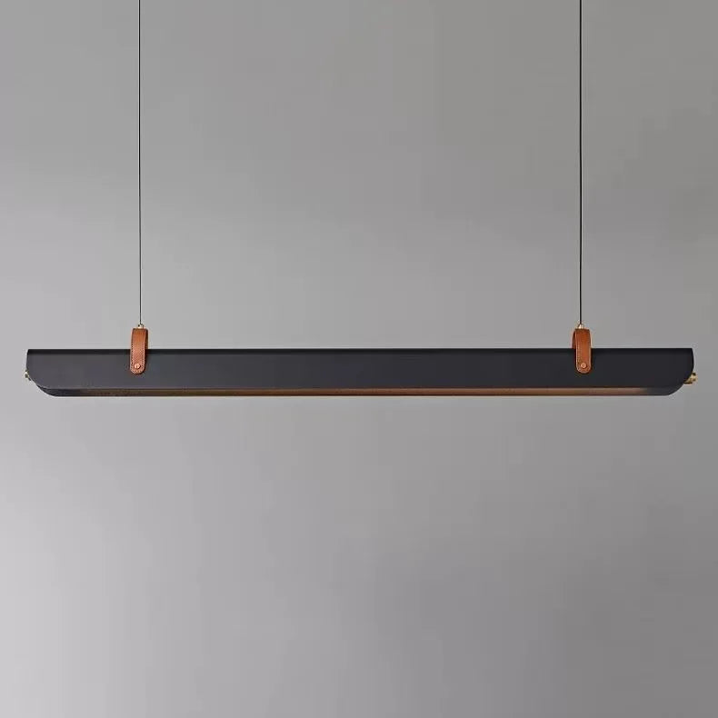 The modern linear Sleek Scroll pendant light from Domus Collective suspended horizontally by two thin cables, featuring a matte black body with copper-colored leather loops and a subtle warm metallic edge, set against a solid gray background.
