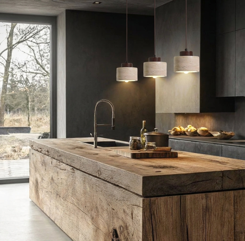 Three short walnut Stone Cylinder Pendant Lamps with travertine shades and dark wood accents, suspended over a rustic reclaimed wood kitchen island for organic modern sophistication, by Domus Collective.