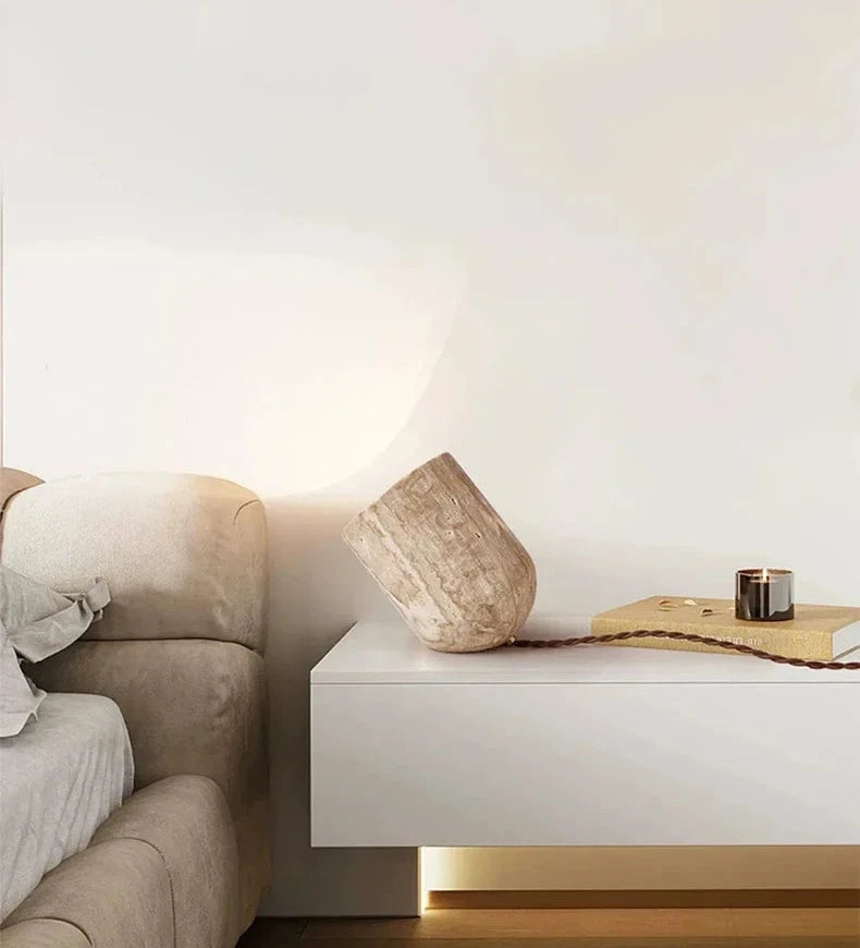 Bedside elegance with the Stone Spotlight Table Lamp, hand-carved travertine projecting warm ambient light in a contemporary bedroom setting, by Domus Collective.
