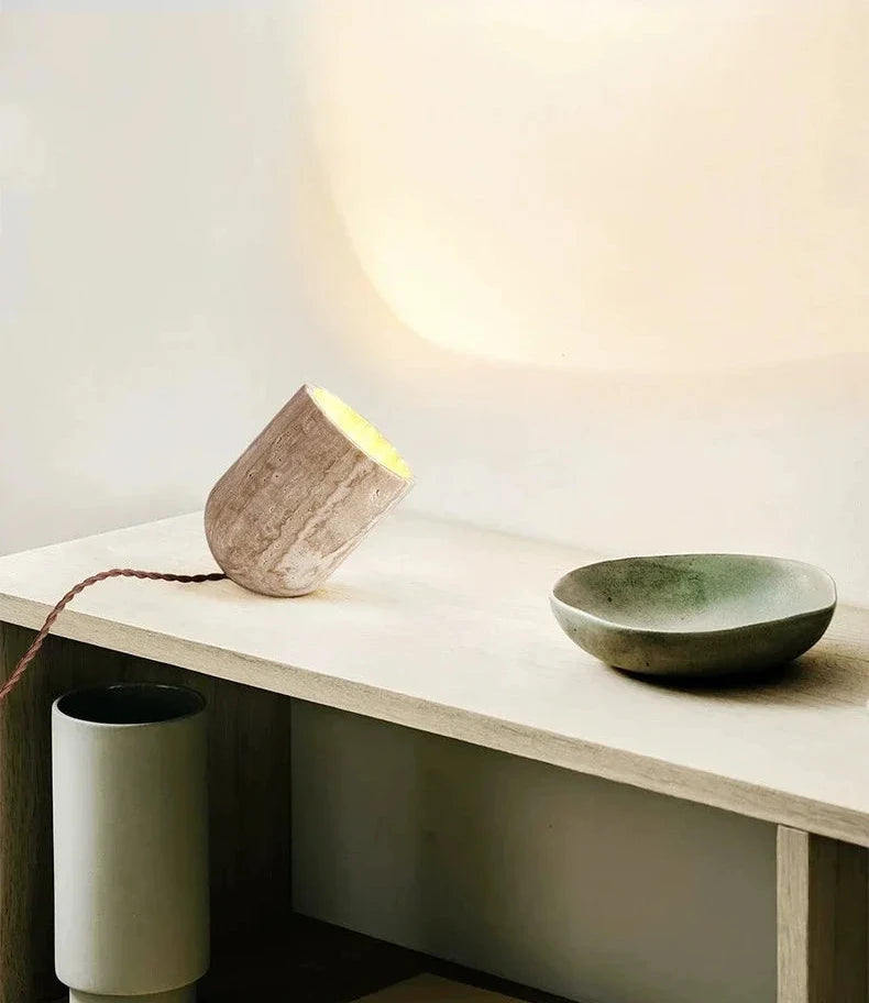 Stone Spotlight Table Lamp casting a gentle arc of warm light, natural travertine with unique tonal variations and twisted fabric cord, styled alongside artisan ceramics, by Domus Collective.