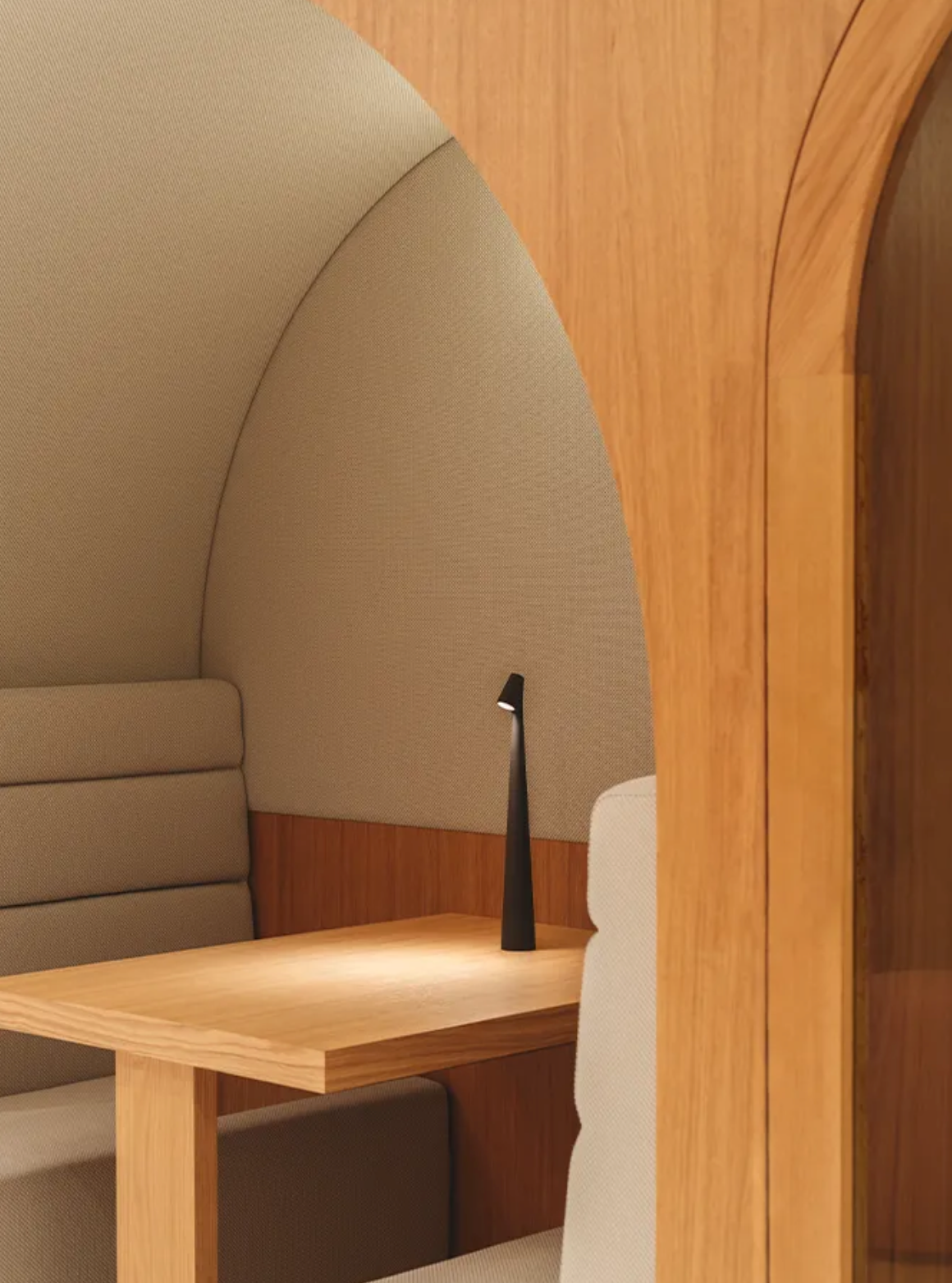 Cozy and Small office pod with wooden desk and beige cushioned walls, with one metallic, rechargeable, Street Pole Light Portable Lamp by Domus Collective ideal for creating warm environment to chat or work.