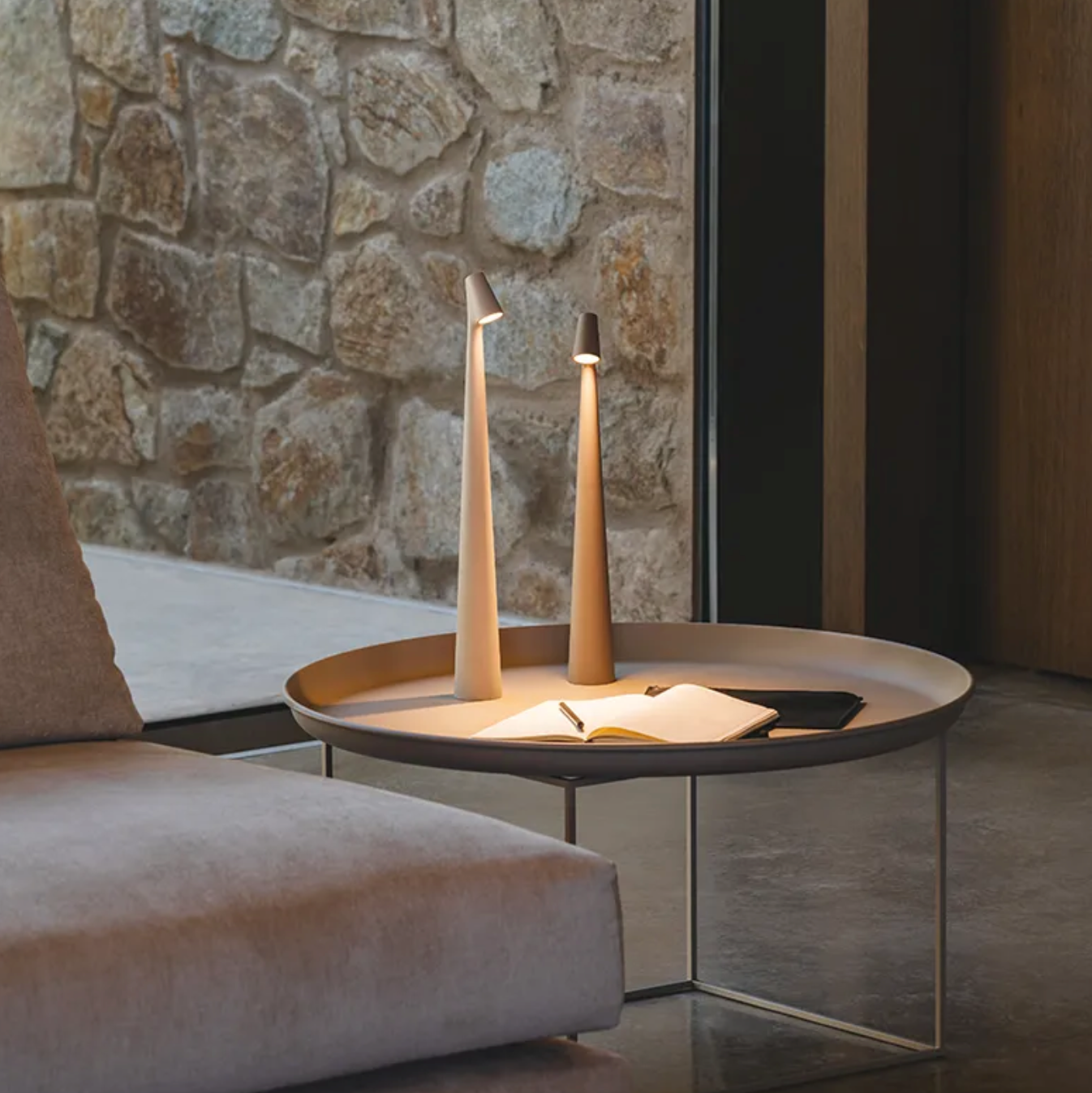 Modern living room with a architectural  stone wall, sofa, and decorative table with two White, Metallic, Street Pole Light Table Lamp by Domus Collective. Perfect for Ambient Lighting.