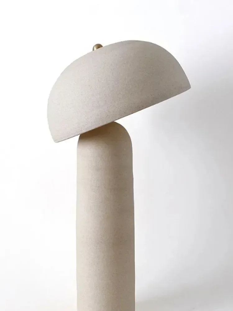 Detail of the Terra Mushroom Table Lamp showing textured sand ceramic finish and adjustable tilting dome shade with brass finial accent, artisan craftsmanship for nature-inspired spaces, by Domus Collective.