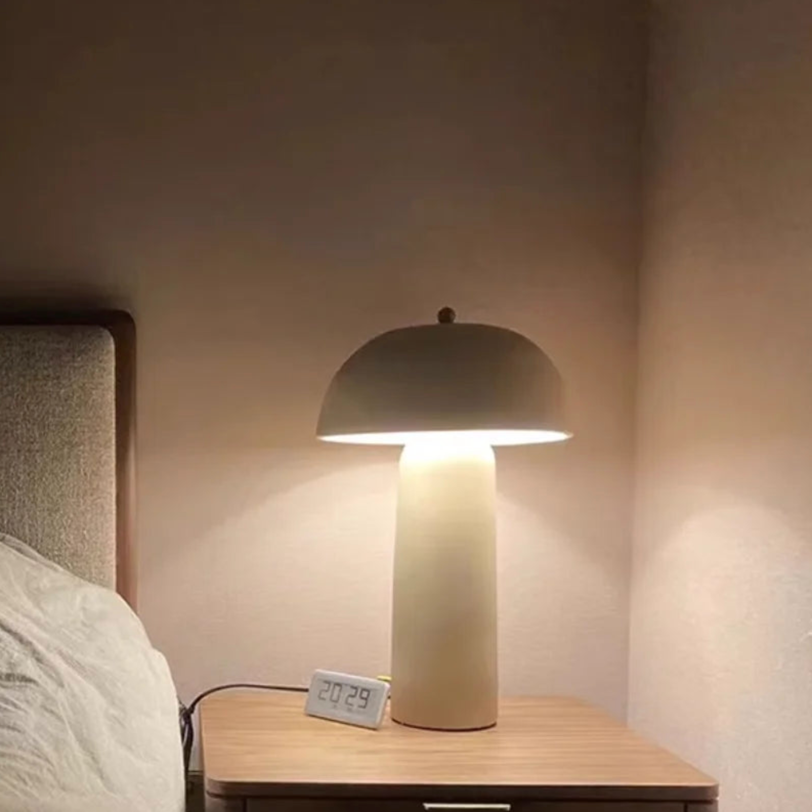 Terra Mushroom Table Lamp casting warm ambient glow on a bedside table, cream ceramic with dome shade providing soft downward illumination for restful bedroom atmospheres, by Domus Collective.
