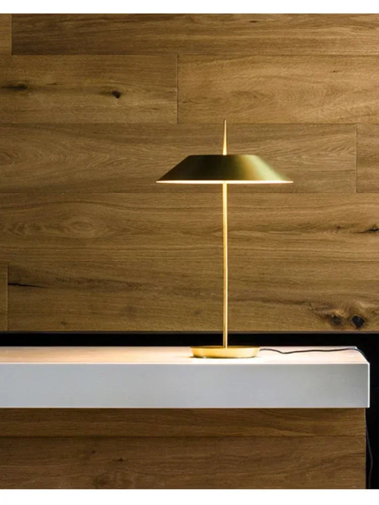 Brushed brass Toothpick Balance Table Lamp displaying its elegant tapered silhouette against rich walnut wood paneling, refined contemporary accent by Domus Collective.