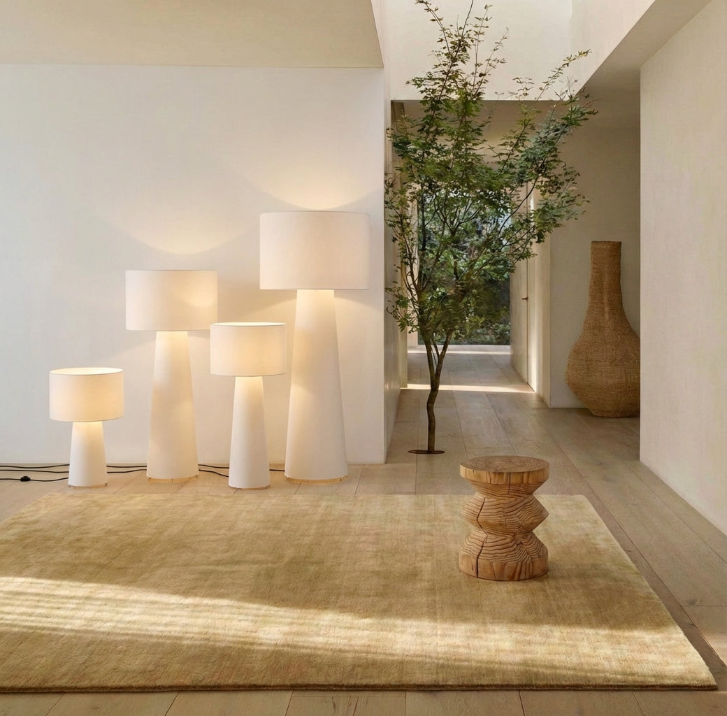 Modern interior with 4 sizes white fabric Tower Glow Floor Lamp, a woven stool, and a tree in a room with a large window. Domus Collective